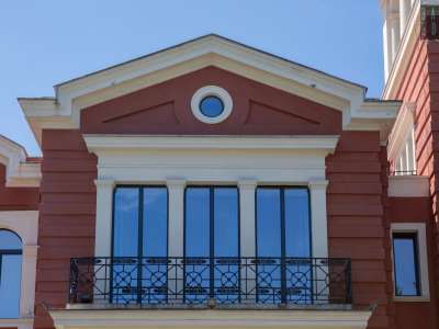 Sul corpo centrale, leggermente aggettante, si aprono invece degli ampi finestroni, di cui quelli superiori dotati di balcone con ringhiera in ferro